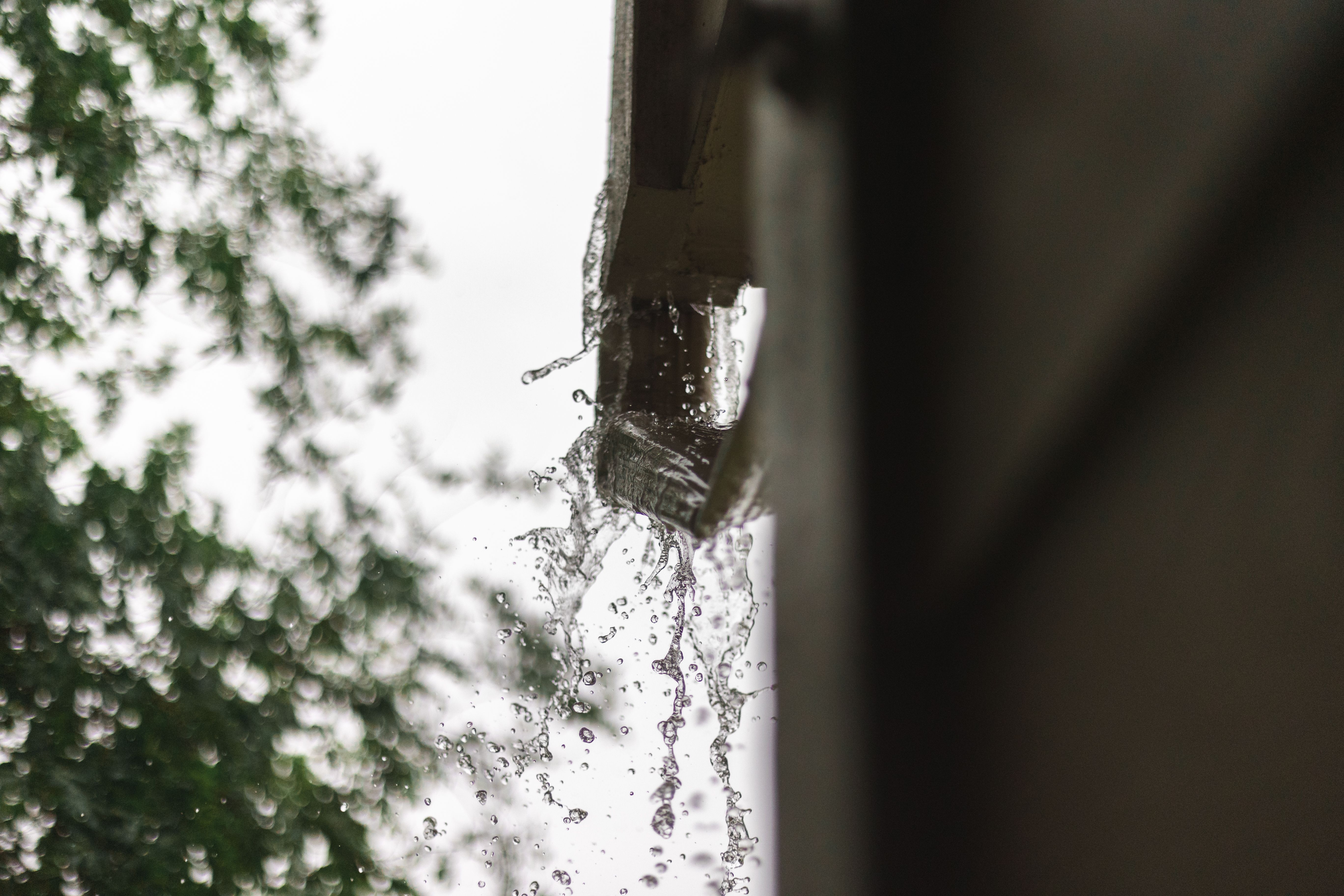 Rainwater flowing from a gutter during a downpour, illustrating why drainage should be checked before an event.
